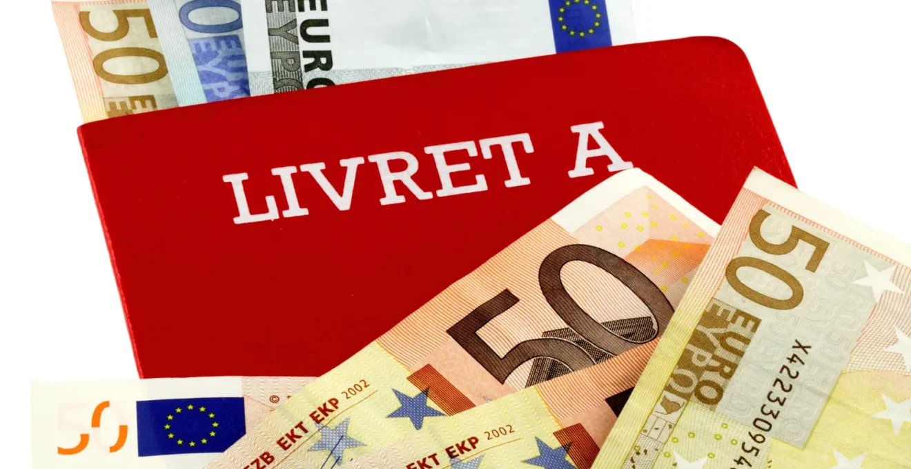 Personne consultant attentivement un relevé bancaire montrant les détails du Livret A sur une table