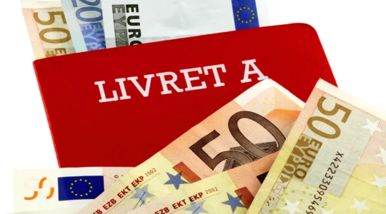 Personne consultant attentivement un relevé bancaire montrant les détails du Livret A sur une table